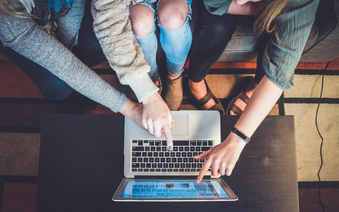 drie mensen die wijzen naar een afbeelding op laptop